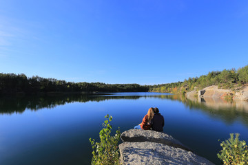 Young loving couple sitting on top of a mountain near a lake