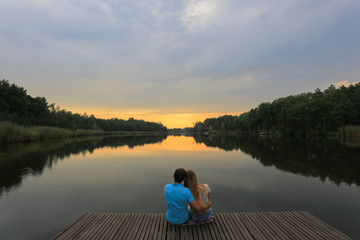 Loving young couple sitting near a lake