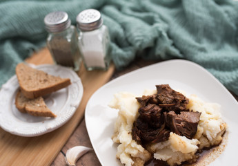Beef tips with gravy on mashed potatoes served on white plate