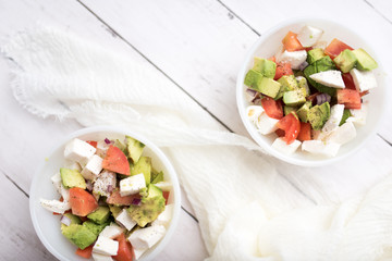 healthy salad from fresh vegetables with avocado, tomatoes and fresh mozzarella cheese served in white bowl