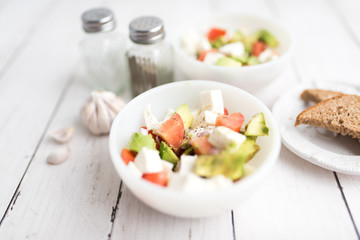 healthy salad from fresh vegetables with avocado, tomatoes and fresh mozzarella cheese served in white bowl