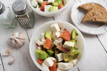 healthy salad from fresh vegetables with avocado, tomatoes and fresh mozzarella cheese served in white bowl