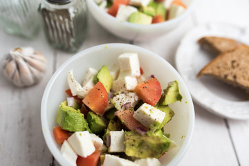 healthy salad from fresh vegetables with avocado, tomatoes and fresh mozzarella cheese served in white bowl