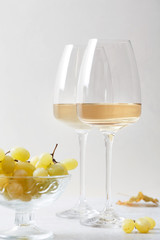 White wine in a glass and grapes on the table. Light background.