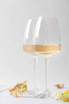 White wine in a glass and grapes on the table. Light background.