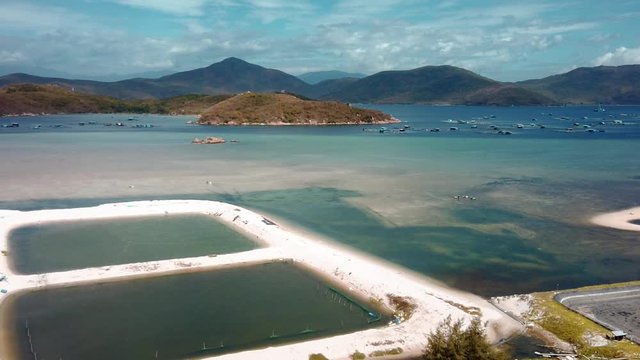 Van phong Bay aerial view establishing shot Floating mariculture fish cages, marine shrimp farming grow-out ponds, coastal buddhist temple, Whale Island. Khanh Hoa province Vietnam