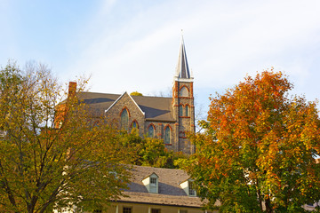 Historic city church in magnificent fall colors at Harpers Ferry, West Virginia, USA. The church on a hillside framed by maple trees.