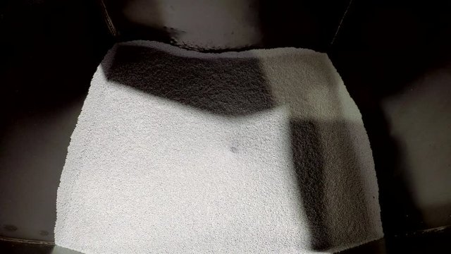 White plastic pellets falling down from a container. Part 3 of 3 1/3 full - empty. Industrial polymers processing.