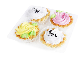 Four different cakes with cream in a plastic container isolated on white background