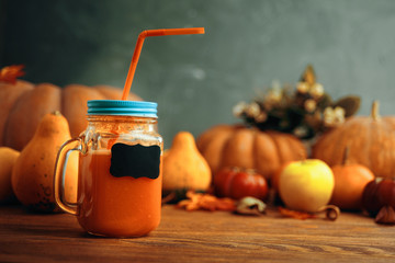 Pumpkins juice in bottles with pumpkins. Cup of pumpkin juice, pumpkins on wooden table. Cup of pumpkin juice, pumpkins and on old wooden table..