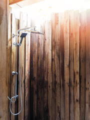 Metal shower in the restroom with rough plank wall no roof.