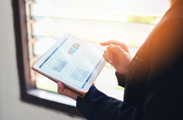 Using a tablet computer for money analyzing graphs summary report chart - Business woman working in office with checking business report in a tablet