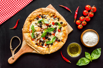 Pizza with tomato, basil, olives, cheese on black background top view