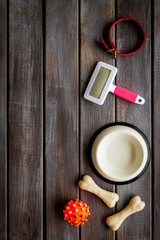 Set of treats and toys for pets with bones, collar and bowl on dark wooden background top view frame copy space