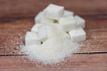 Fototapeta na wymiar Heap of white sugar on wooden table background - sugar cubes