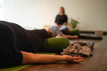Selective focus photo of a camera filming a professional yoga teacher explaining positions in a group session of yoga