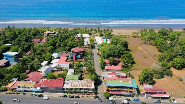 Aerial: Cars Driving in Coastal City Near Hotels and the Beach With Vibrant Blue Water - Jaco, Costa Rica