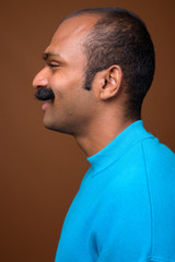 Obraz premium Closeup profile view of happy Indian man with mustache wearing blue sweater