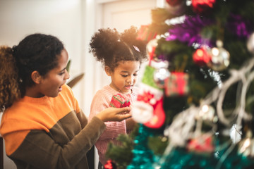 Merry Christmas and Happy Holiday. Mom and daughter decorate the Christmas tree . The morning before Xmas. .Happy little smiling girl .