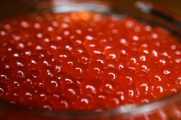 Glass jar with red caviar on a wooden surface. Largest species. Horizontal photography