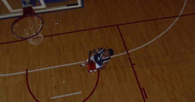 OVERHEAD HIGH ANGLE JIB SHOT African American Black College Male Basketball Player Practicing Dunks Alone On The Indoor Court. 4K UHD 50 FPS SLOW MOTION RAW Graded Footage