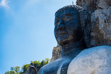 Suphan Buri, Thailand - October 27, 2019: Rock Buddha Statue at Wat Khao Tham Thiam, Rock Buddha statue carved from cliffs of the rocky mountain at Suphan Buri, Thailand