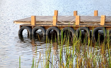 Obraz premium The pier on the river is new wooden. The pier is made of boards, logs, rope.