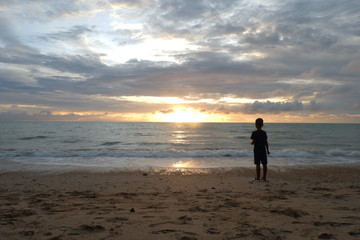young man walking on the beach at sunset
