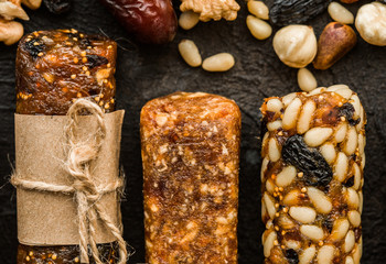 Bunch of mixed gluten free energy bars with dried fruit & various nuts, wooden background. Healthy vegan super food, different fitness diet snacks for sporty lifestyle. Top view, copy space.