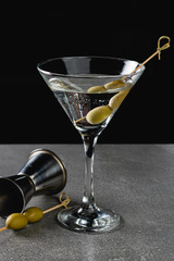 Drink Dry Martini with Green Olives on Stone Background.