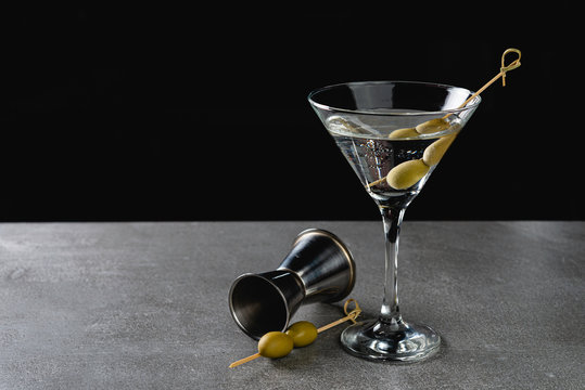 Drink Dry Martini with Green Olives on Stone Background.