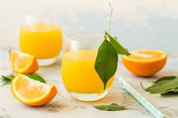 Glass of fresh orange juice,ripe orange fruit and slices on natural .Freshly squeezed orange juice with drinking straw,orange fruit and orange slices.