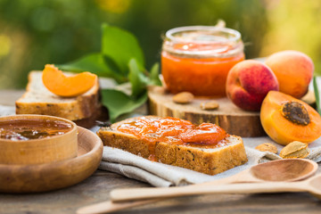 Apricot jam and ripe apricots on the wooden natural table.