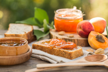 Apricot jam and ripe apricots on the wooden natural table.