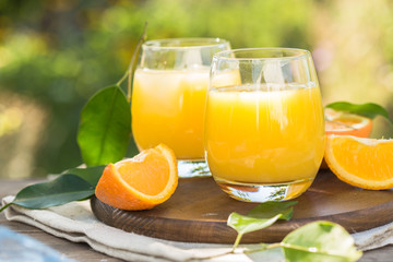 Glass of fresh orange juice,ripe orange fruit and slices on natural .Freshly squeezed orange juice with drinking straw,orange fruit and orange slices.