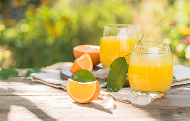 Glass of fresh orange juice,ripe orange fruit and slices on natural .Freshly squeezed orange juice with drinking straw,orange fruit and orange slices.