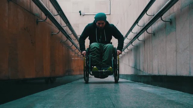 Disabled man in wheelchair getting up on the long special ramp sometimes leaning on the railing