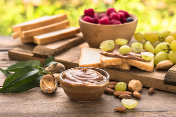Almond butter in jar with almonds and fruits on wooden natural background. 