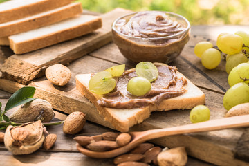 Almond butter in jar with almonds and fruits on wooden natural background. 
