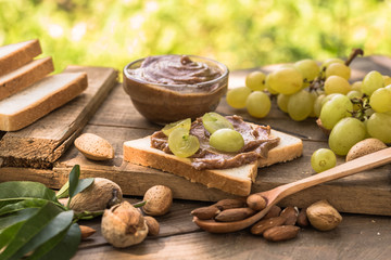 Almond butter in jar with almonds and fruits on wooden natural background. 