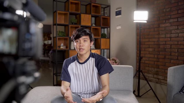 Asian young man blogger recording vlog talking to camera when work at home