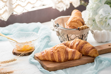 Fototapeta na wymiar Freshly baked croissants with orange jam on light background
