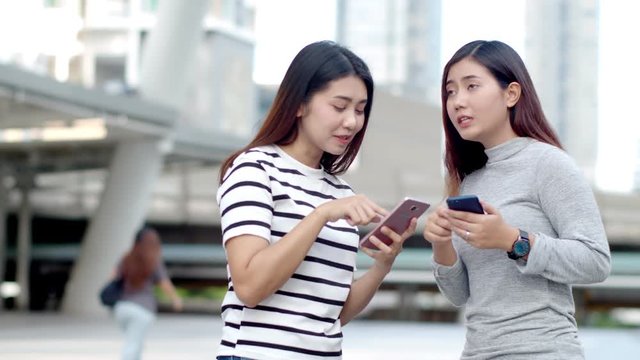 Two Teenager travellers checking map on smartphone in city