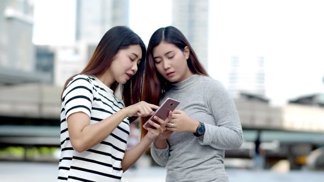 Two Teenager travellers checking location map on smartphone