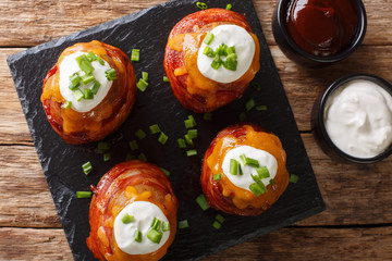 Volcano potatoes with cheese, bacon, sour cream and green onions close-up. Horizontal top view