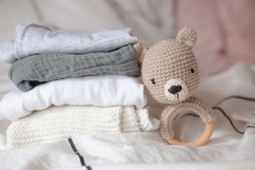baby clothes with diapers are stacked with a pacifier and a toy bear