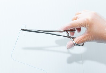 Doctor holding surgical forceps suture needle, suturing material. Suture thread. Nylon surgical...