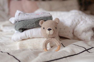 baby clothes with diapers are stacked with a pacifier and a toy bear