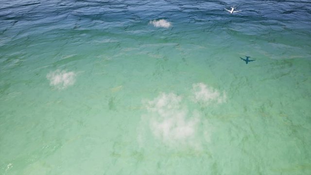 Plane flying above sea surface realistic animation. 3d aircraft passing over ocean with calm waves and clouds reflection in water footage. Summer tourism concept, plane flight aerial view video