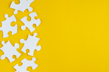 White puzzles composition on yellow background. Flat lay